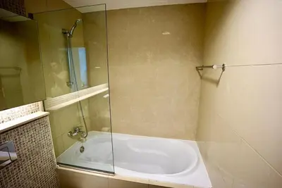 a bathroom with a shower and a tub with a glass door at Elite Downtown 1BR Stylish 1BR in Dubai