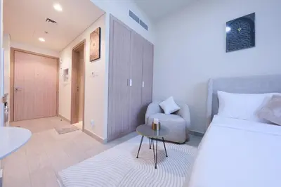 a bedroom with a bed and a chair and a table at Premium Studio near Meydan Azizi Riviera 46 in Dubai