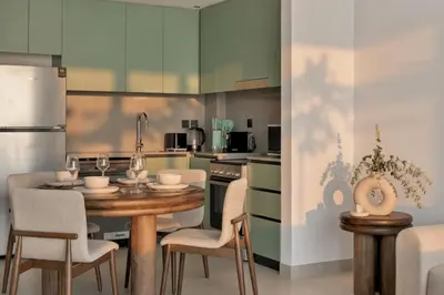 a kitchen with a wooden table and chairs and a kitchen with green cabinets at 1 Bedroom Apartment in Central Park, City Walk in Dubai