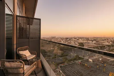 a balcony with two chairs and a view of a city at 1 Bedroom Apartment in Central Park, City Walk in Dubai