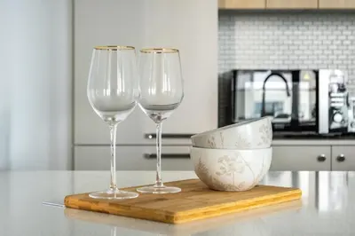 two wine glasses and a bowl on a cutting board at GuestReady - 1BR l Elegant City Escape in Dubai