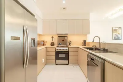 a kitchen with stainless steel appliances and white cabinets at Elite Burj Khalifa Fountain 4 BR Flat in Dubai