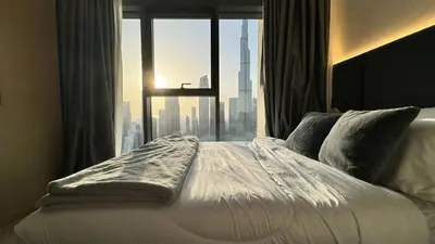 a bed in front of a window with a city view at Elite Burj Khalifa Fountain 4 BR Flat in Dubai
