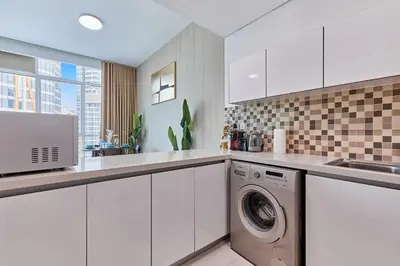 a white kitchen with a washing machine in it at Bright 1 BHK in Prime Location in Dubai