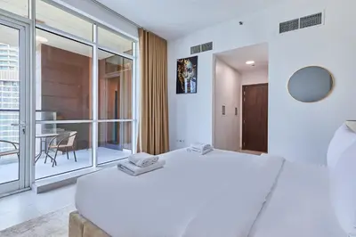 a bedroom with a large white bed and a table at Bright 1 BHK in Prime Location in Dubai