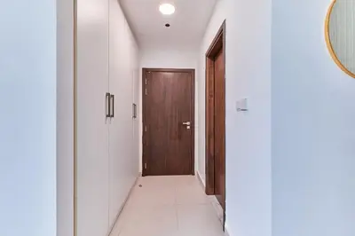 a hallway with white walls and a wooden door at Bright 1 BHK in Prime Location in Dubai
