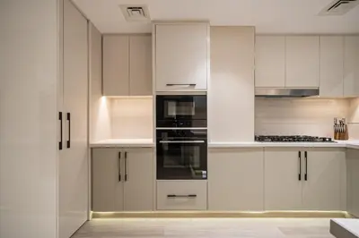 a kitchen with white cabinets and a stove top oven at Paradise Retreats 3BR Burj Khalifa & Fountain view in Dubai