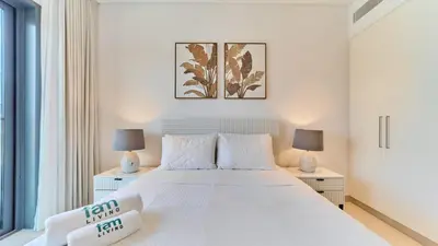 a bedroom with a large white bed with two lamps at Stylish 1 Bedroom in Viridian City Walk in Dubai