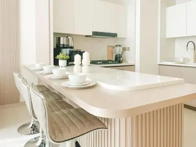 a kitchen with a large white counter with chairs at Calm Luxe 1BR Suite in Binghatti Royale with Parking! in Dubai