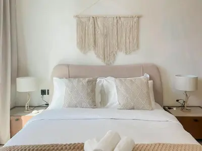 a bedroom with a white bed with two lamps at Warm Minimal 1BR in Binghatti Tulip with Free Parking! in Dubai