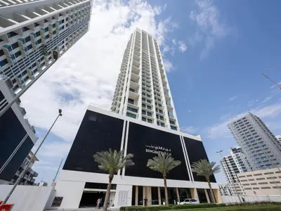 a tall building with palm trees in front of it at Warm Minimal 1BR in Binghatti Tulip with Free Parking! in Dubai