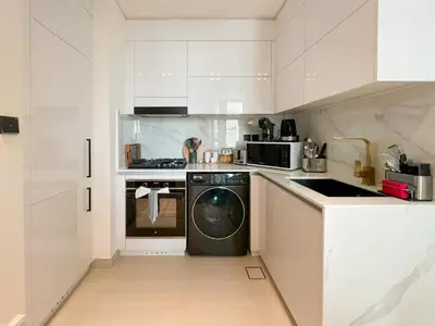 a white kitchen with a dishwasher and a washer at Warm Minimal 1BR in Binghatti Tulip with Free Parking! in Dubai