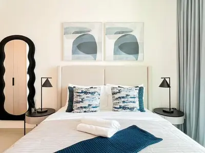 a bedroom with a bed with blue and white pillows at Binghatti Azure Ethereal Studio Haven with Pool & Gym! in Dubai
