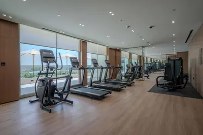 a gym with a row of treadmills and ellipticals at Binghatti Azure Ethereal Studio Haven with Pool & Gym! in Dubai