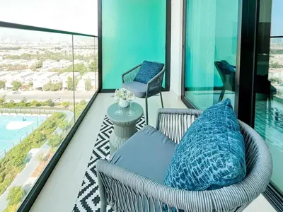 a balcony with a wicker chair and blue pillows at Binghatti Azure Ethereal Studio Haven with Pool & Gym! in Dubai