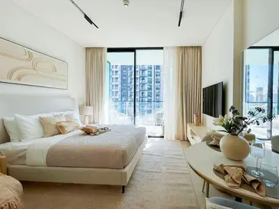 a white bedroom with a large bed and a table at Warm-Toned Studio with City Views in Binghatti Azure in Dubai