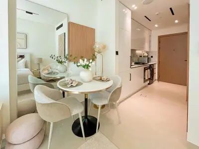 a kitchen and living room with a table and chairs at Warm-Toned Studio with City Views in Binghatti Azure in Dubai