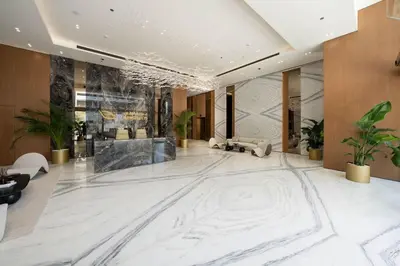 a lobby with a large white marble floor and chairs at Warm-Toned Studio with City Views in Binghatti Azure in Dubai