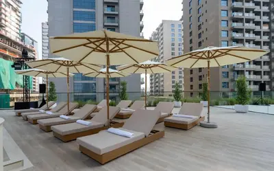 a row of chairs and umbrellas on a patio at Calm 1BR Haven with Private Pool in Binghatti Royale in Dubai