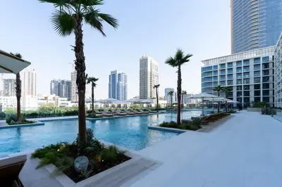 a swimming pool with palm trees in a city at Softline Studio with Open Views in Binghatti Phoenix! in Dubai