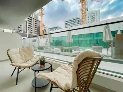 a balcony with two chairs and a table at Family-Friendly 1BR Apt with Study Room and Pool Views! in Dubai