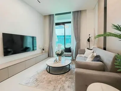 a living room with a couch and a tv at Family-Friendly 1BR Apt with Study Room and Pool Views! in Dubai