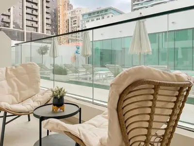 a balcony with two chairs and a table andwindows at Family-Friendly 1BR Apt with Study Room and Pool Views! in Dubai