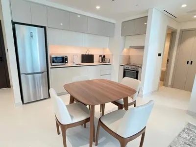 a kitchen with a wooden table and white chairs at Stunning and Cozy Home with Marina and Sea View in Dubai