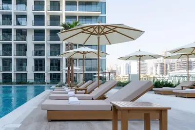 a pool with lounge chairs and umbrellas on a building at Elevated Studio Living at Binghatti Phoenix in Dubai