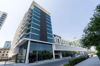 a large building with glass windows on a street at Elevated Studio Living at Binghatti Phoenix in Dubai