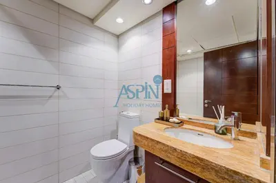 a bathroom with a sink and a toilet and a mirror at Aspin Brand New Premium Studio with Pool View - Burj Views in Dubai