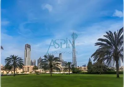 a park with palm trees in front of a city at Aspin Brand New Premium Studio with Pool View - Burj Views in Dubai