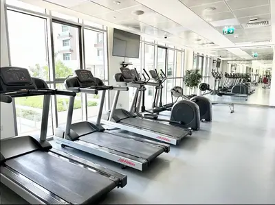 a gym with rows of treadmills and elliptical machines at 2 Bed with Direct Park Access - Calm and Peaceful in Dubai