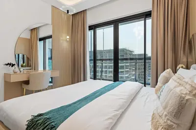 a bedroom with a bed and a desk and windows at Modern 1BR Apartment w Balcony in Meydan in Dubai
