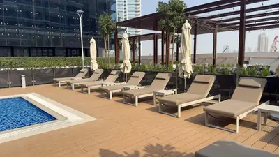 a row of lounge chairs and a pool on a building at Modern 1BR Apartment w Balcony in Meydan in Dubai