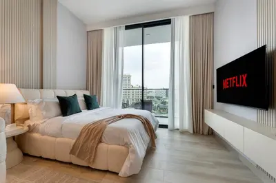 a bedroom with a large bed and a large window at Oxford Gardens Premium Studio with Cinema & Game Room in Dubai