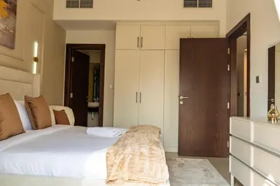 a bedroom with a white bed and a wooden door at Werova - Urban Living 1BR Apartment in JVC in Dubai