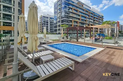 a swimming pool with two chairs and umbrellas and a pool at Stylish Riviera Studio Near Downtown in Dubai