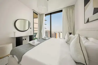 a bedroom with a large white bed with a large window at VayK - Stylish 2BR & Maids Apartment in Sobha Hartland in Dubai