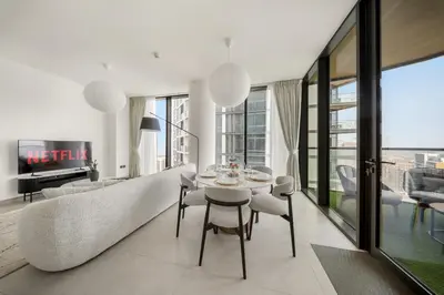 a living room with a table and chairs and a couch at VayK - Stylish 2BR & Maids Apartment in Sobha Hartland in Dubai