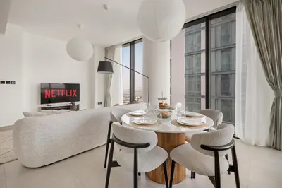 a living room with a table and chairs and a couch at VayK - Stylish 2BR & Maids Apartment in Sobha Hartland in Dubai