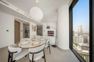 a dining room with a table and chairs and a window at VayK - Stylish 2BR & Maids Apartment in Sobha Hartland in Dubai