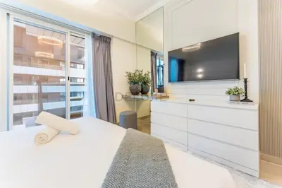 a bedroom with a white bed and a tv at Minutes from Marina Promenade, Surrounded by Shops, and a Short Drive to Ain Dubai, Opal Tower, Dubai Marina by Deluxe Holiday Homes in Dubai