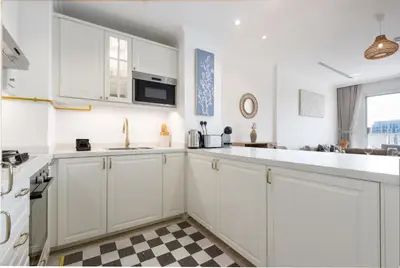 a kitchen with white cabinets and a checkered floor at Relaxing 1BR Peaceful Family Living in JVC in Dubai