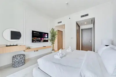 a white bedroom with a white bed and a tv at 2BR Beachfront Apartment at Palace Beach Residence in Dubai