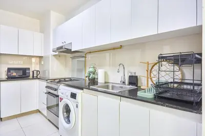 a white kitchen with a sink and a washing machine at Urban and Central - 1BR at Binghatti Gateway in Dubai