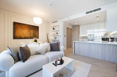 a living room with a couch and a kitchen at Brand New Exclusive 2BR, Burj and Canal View in Dubai