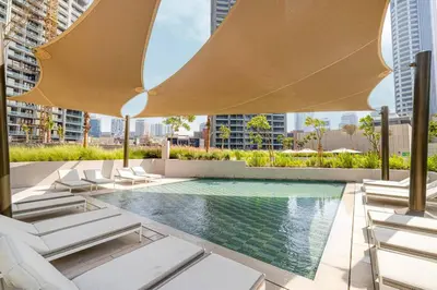 a swimming pool with lounge chairs and a large umbrella at Brand New Exclusive 2BR, Burj and Canal View in Dubai