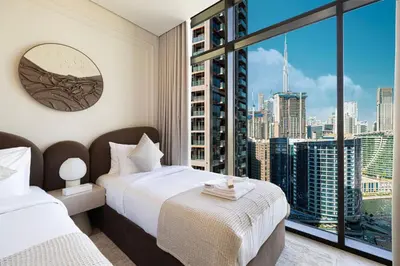 a bedroom with two beds and a large window at Brand New Exclusive 2BR, Burj and Canal View in Dubai