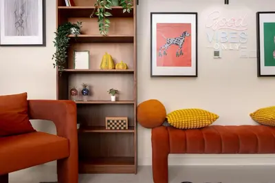 a living room with an orange couch and shelves at 5-Star Living | Luxury 2B & Amenities in Dubai